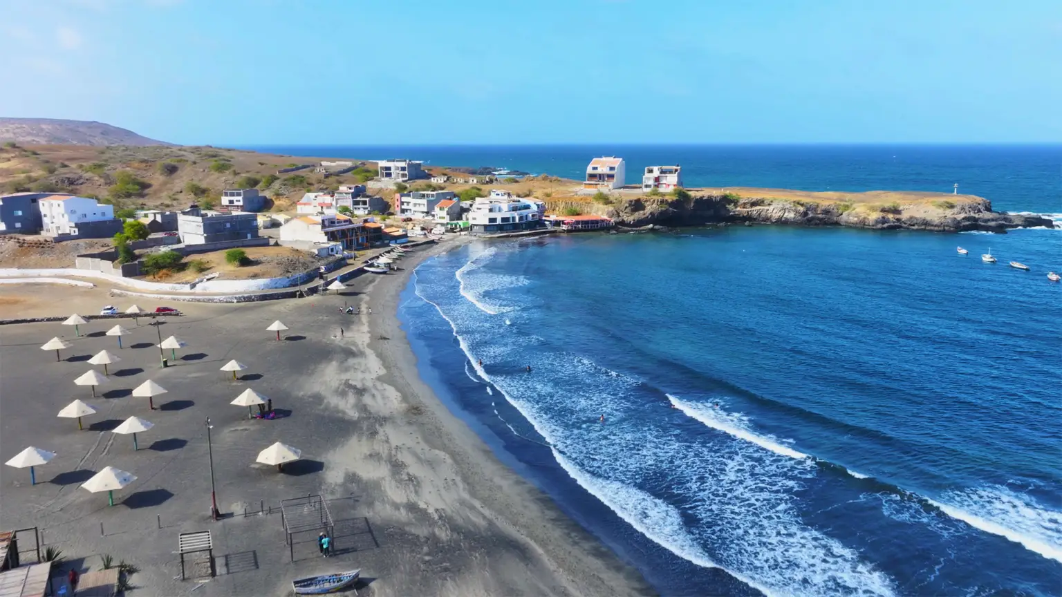 Secluded Praia Baixo Beach on Santiago Island, Cape Verde, with rugged cliffs, black volcanic sand, and crystal-clear waters.