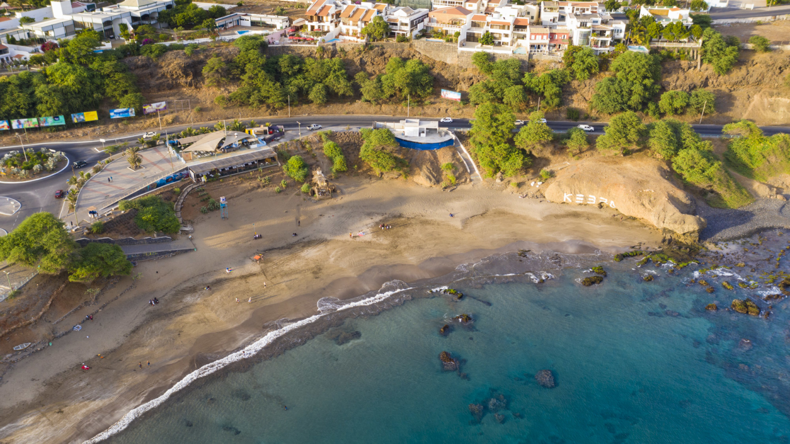 Quebra Canela Beach in Praia, Santiago Island, Cape Verde, with golden sand, calm waters, and vibrant beachfront restaurants and bars.